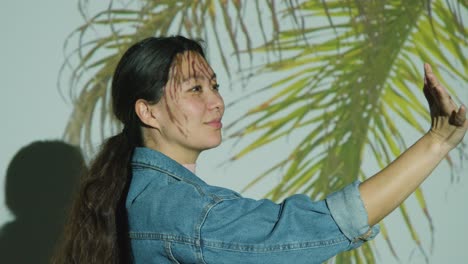 woman visiting immersive art exhibition with images of palm leaves being projected onto her face