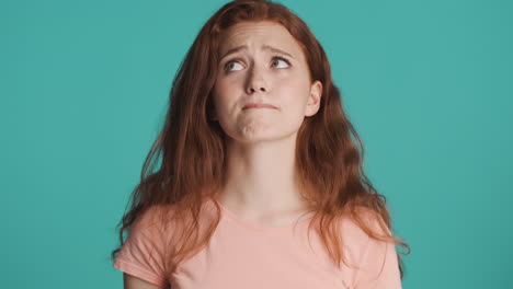 Redheaded-girl-in-front-of-camera-on-turquoise-background.