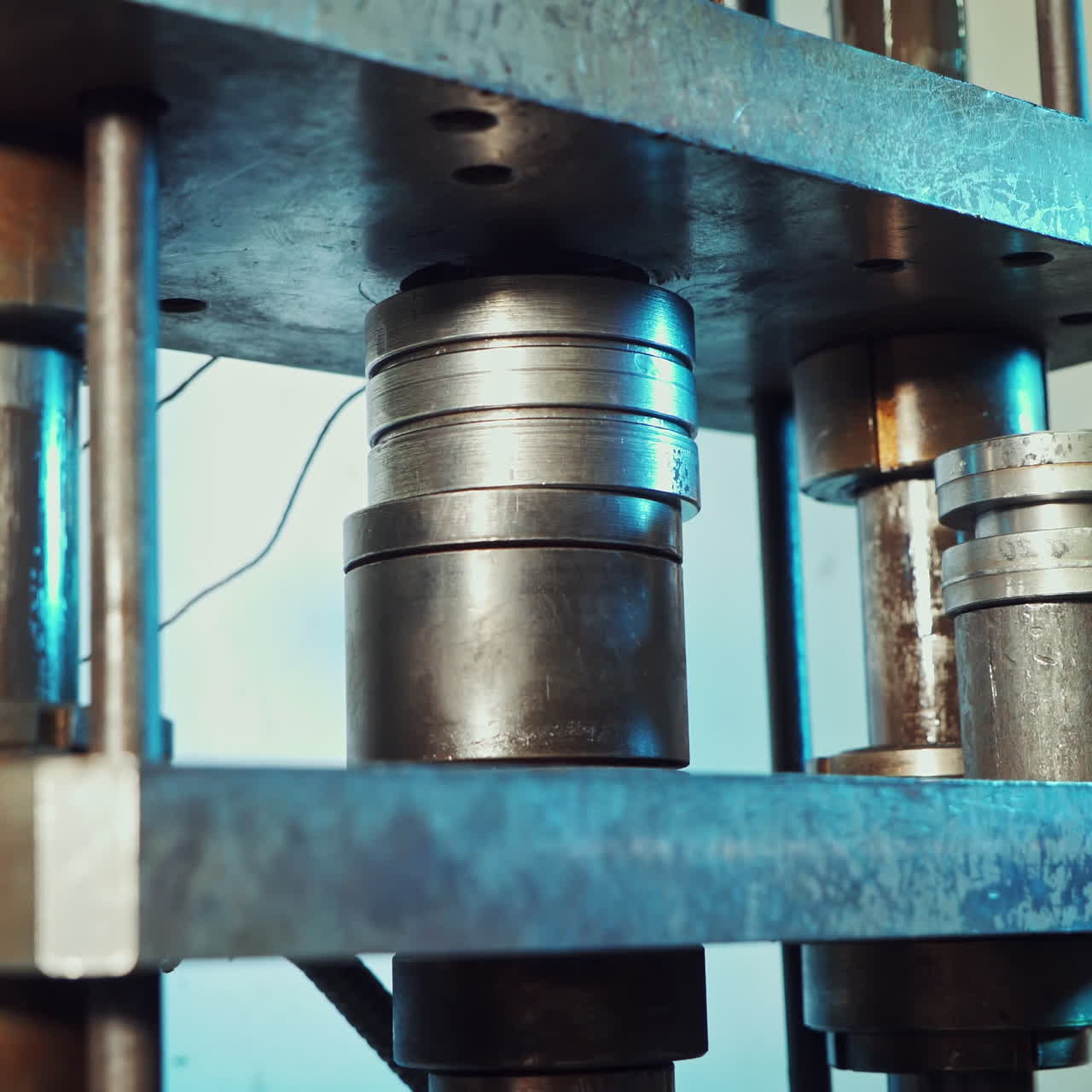 Close up shot of a punch press forming metal parts in the industrial factory. Worker puts some parts to the press mold.