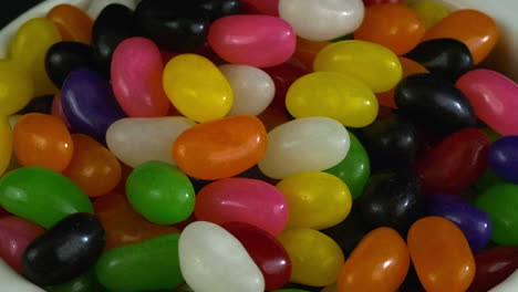 candy closeup macro: sweet sugary beans rotate in white bowl