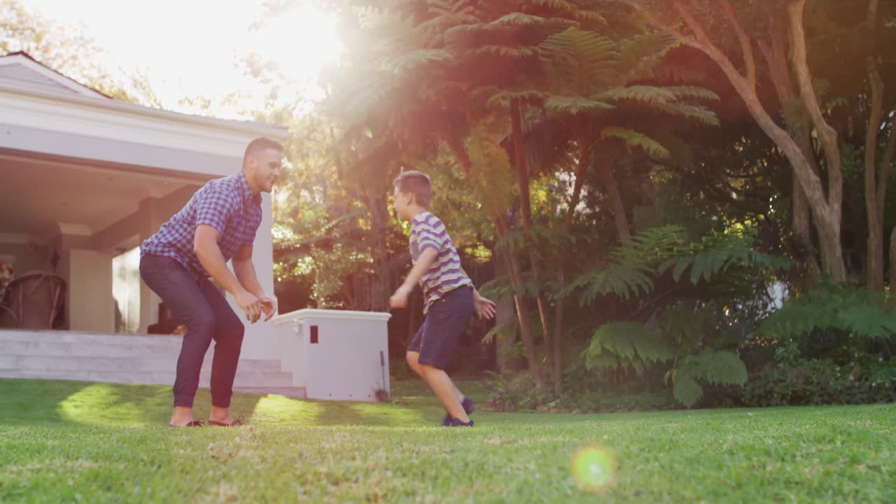 행복한 백인 아들이 달려서  ⁇ 은 정원에서 아버지의 팔에 뛰어들고