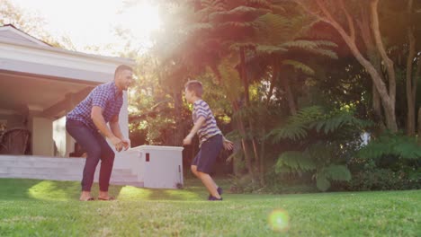 Happy-caucasian-son-running-and-jumping-into-the-arms-of-father-in-sunny-garden