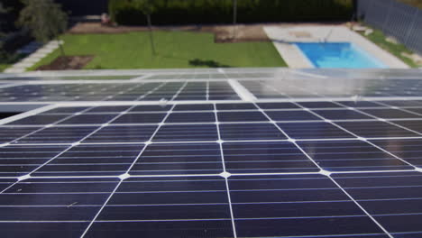 Paneles-Solares-En-El-Techo-De-La-Casa,-Debajo-Se-Puede-Ver-La-Piscina-Y-El-Césped-Verde.