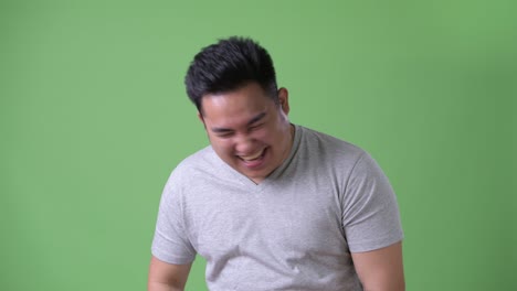 초록색 배경에 젊은 잘생긴 과체중 아시아인