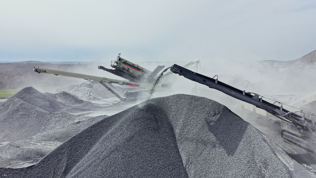 Granite quarry shows machinery working and piles of stone at a busy site during the day