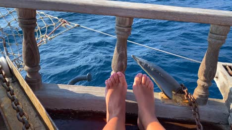 Funny-female-dancing-feet-on-a-wooden-sailing-boat-and-sea-waves,-fun-summer-vacation,-moving-boat,-sunny-holiday,-4K-shot