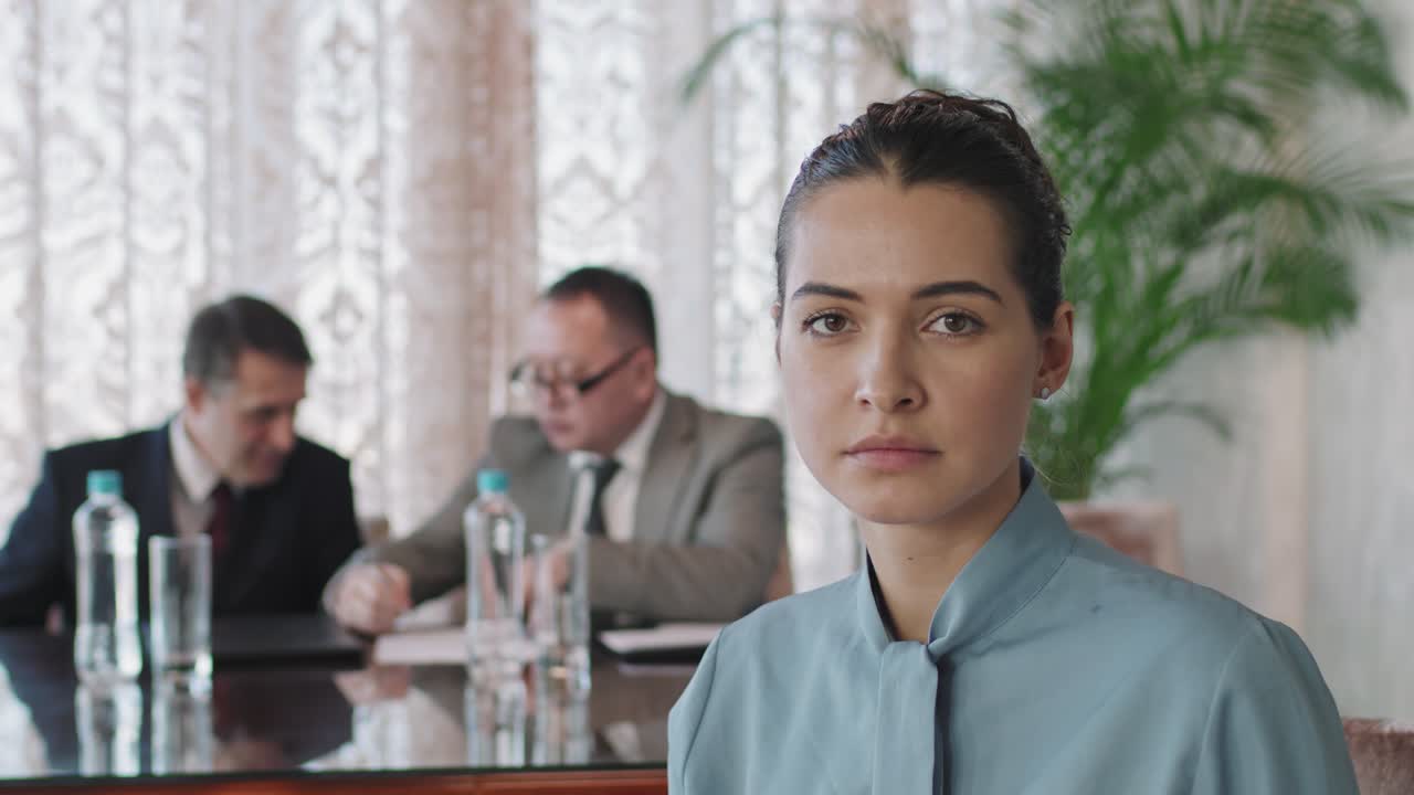 forretningskvinde på et forretningsmøde på kontoret, der kigger på kameraet