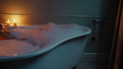 woman relaxing in a bubble bath with candles