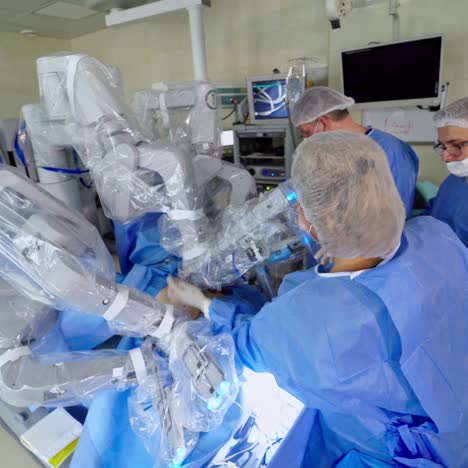surgery with medical robot in operating room. medical specialists change machine arm of a robotic machine. doctors work near futuristic robotic machine. top view