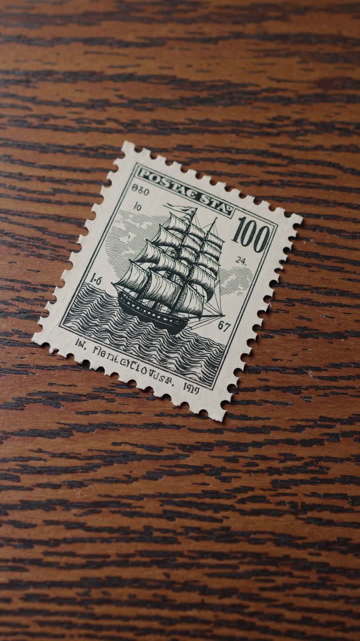 Video ravvicinato di un francobollo vintage con il disegno di una nave su una superficie di legno, ripreso
