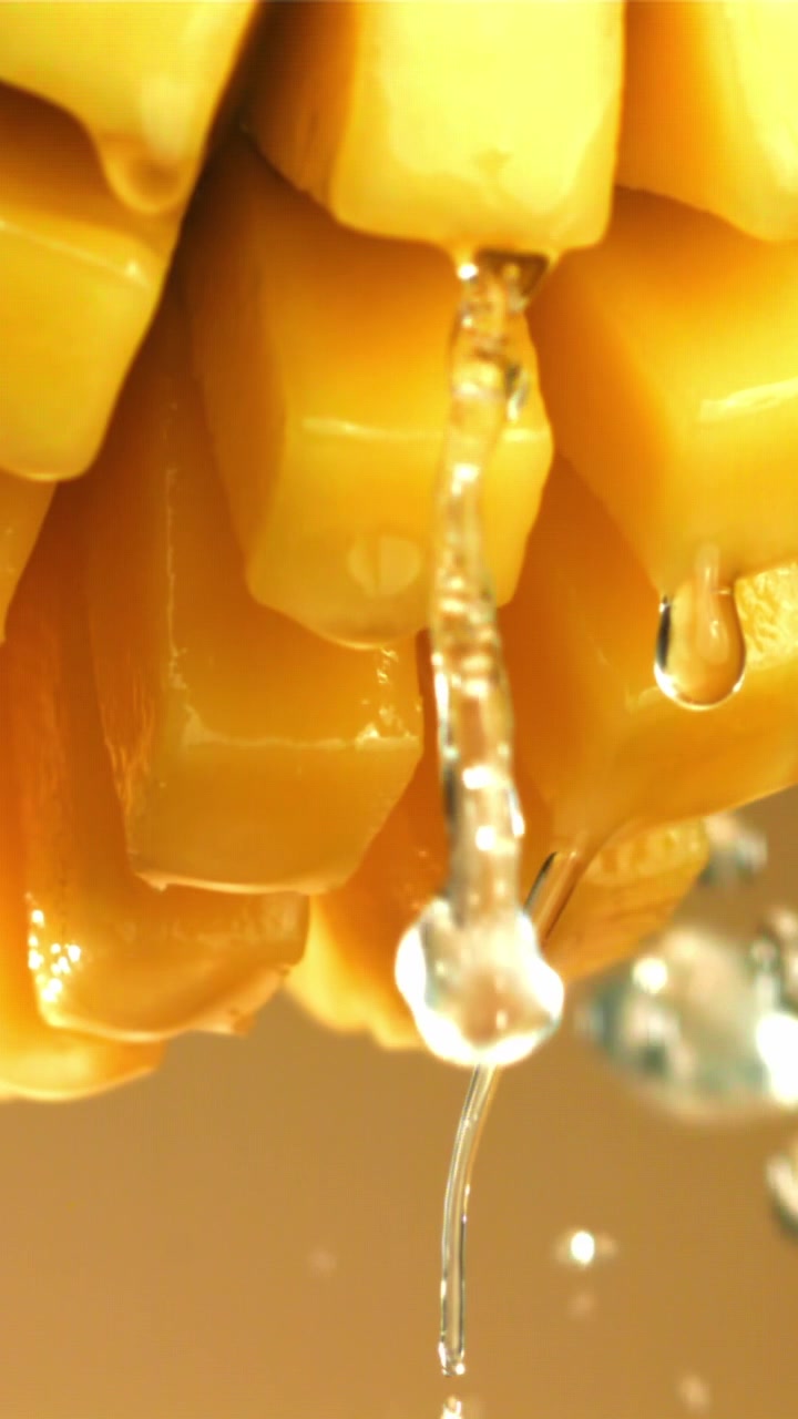 Acqua che gocciola al rallentatore su pezzi di frutta gialla fresca.