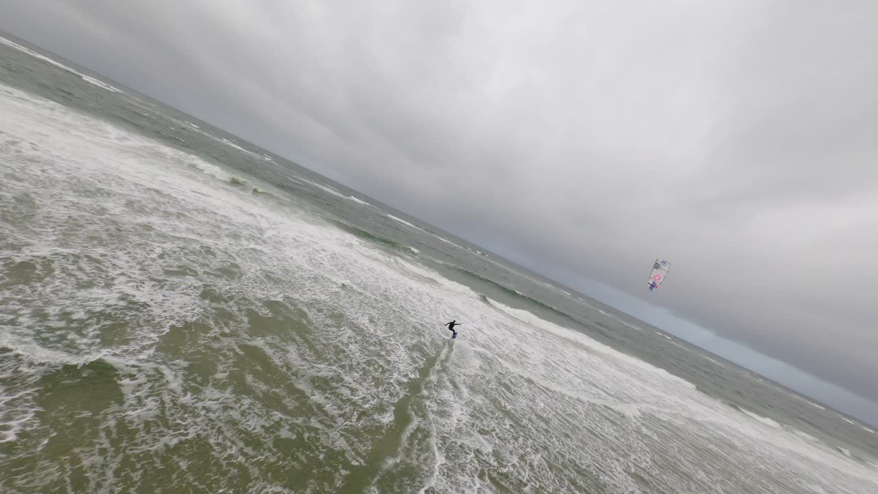 vista fpv del atleta surfista de cometas montando olas rompientes en la playa de sylt