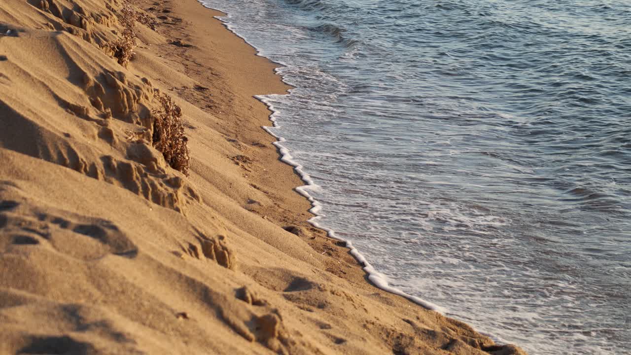 Lysbølger og sandstrand ved solnedgang