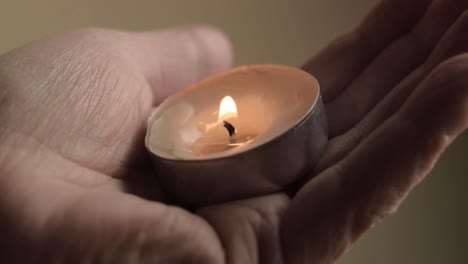 Vela-De-Té-Encendida-Ahuecada-En-La-Palma-De-Una-Mano