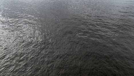 An-aerial-view-over-the-green-waters-of-the-Atlantic-Ocean,-off-Rockaway-Beach-in-New-York