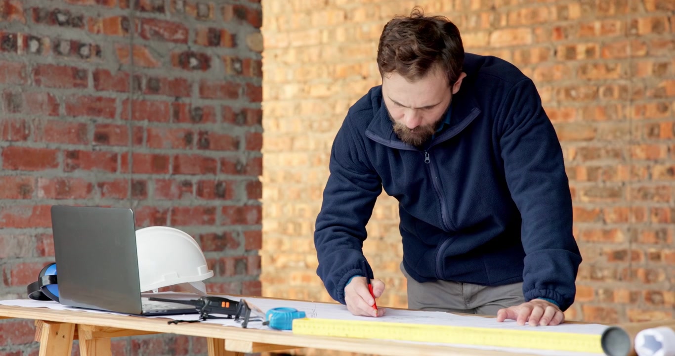 Architect Working on Construction Blueprints in Unfinished Building