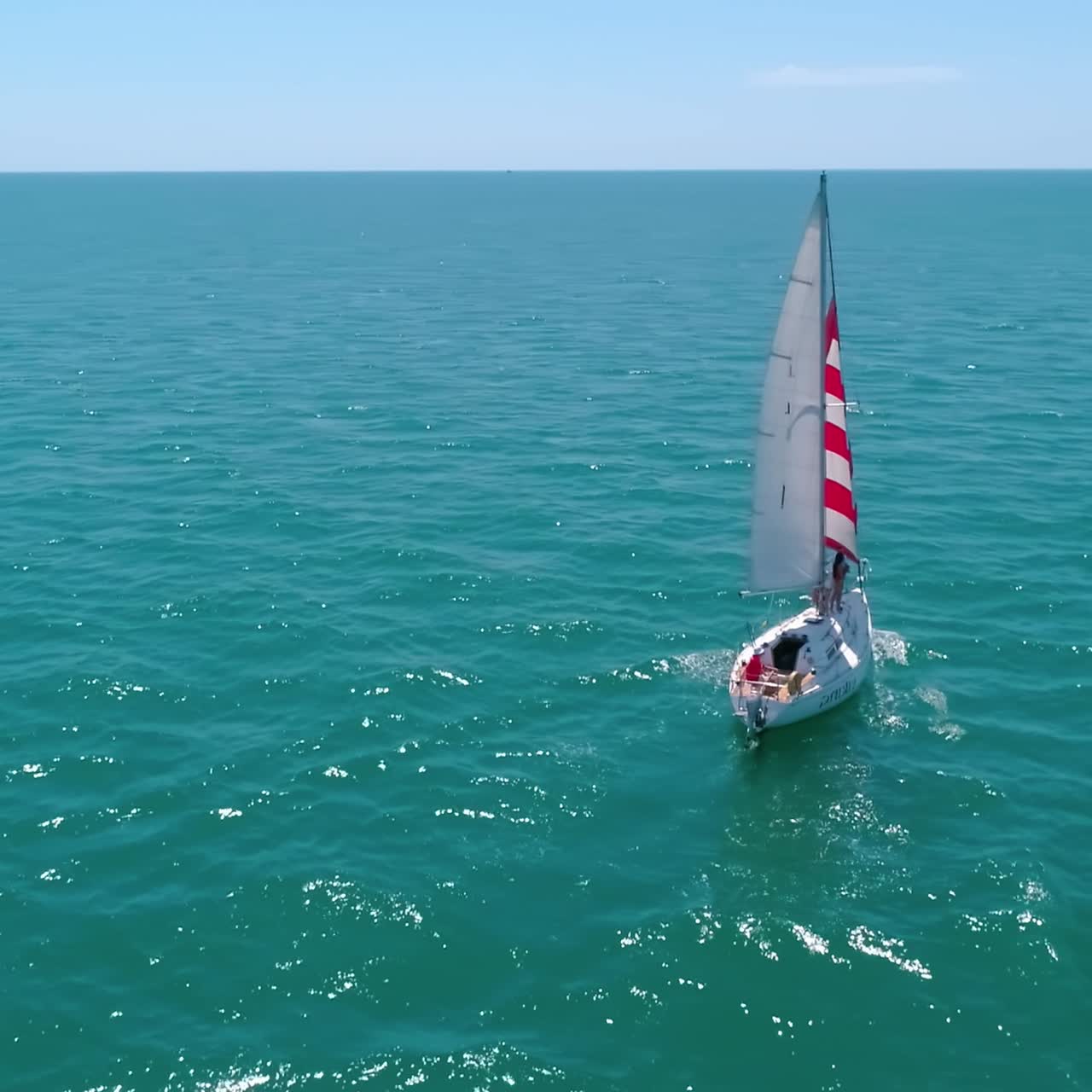 Sailboat floating on sea. Sailing yacht at sea bay. Sun seascape with sail boat on the background of the city. Small ship at open sea. Circling view