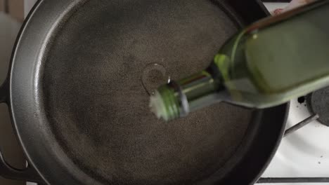 oil being poured in a cast iron skillet prior to cooking - overhead view