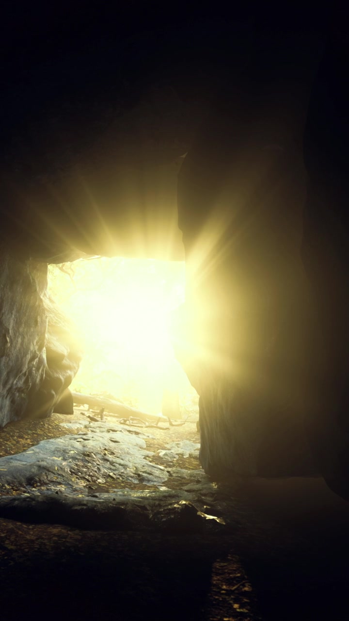 La luce calda si riversa nella grotta buia illuminando le rocce e il terreno