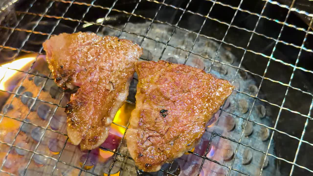 Nærbillede af marmorerede oksebøffer, der steger over åben ild på en japansk kulgrill.