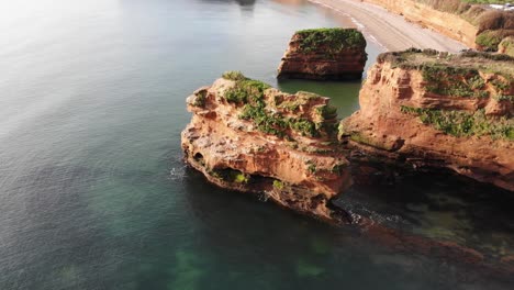 toma estacionaria aérea de una pila de arenisca roja de la costa en ladram bay devon, inglaterra
