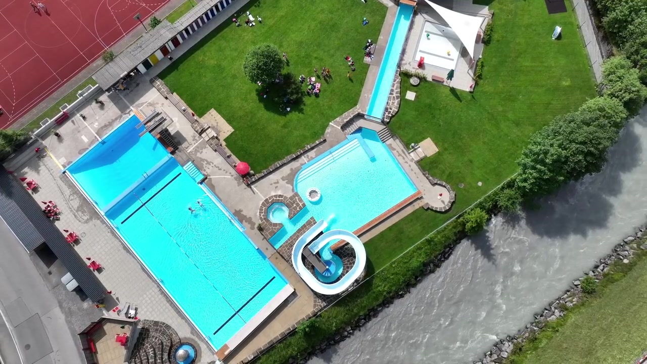 Offentligt feriested med grønt græs og pool i Schweiz, luftfoto