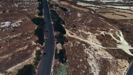 aerial following group quad biking down road in rugged landscape gozo, malta