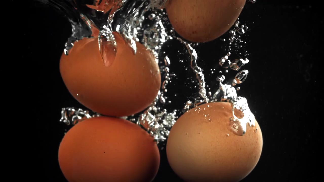 Fresh Brown Eggs Splashing into Water with Bubbles
