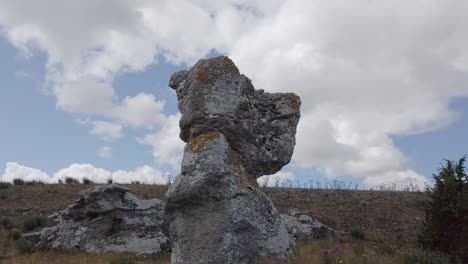 rock outcrop in natural area standing out against sky with clouds, arc shot