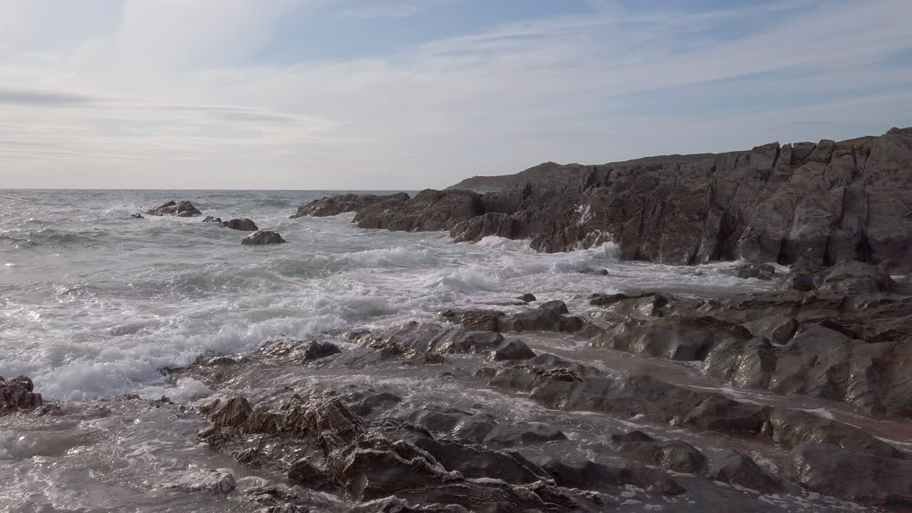 olas rompiendo contra una cala rocosa en una noche de verano