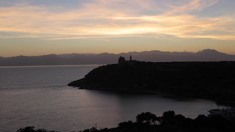 Eine-Malerische-Landschaft-Nach-Sonnenuntergang-Einer-Halbinsel-Einer-Bucht-Mit-Wunderschönem-Goldenen-Himmel-über-Bergen-Im-Hintergrund