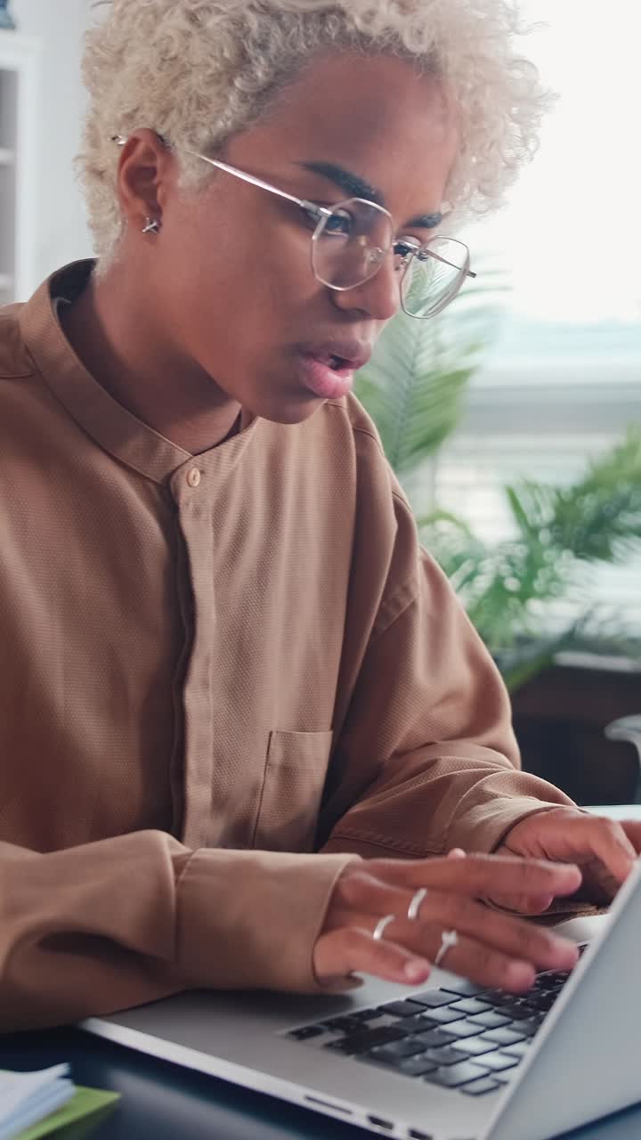 Young african american woman journalist typing article in laptop sits in office