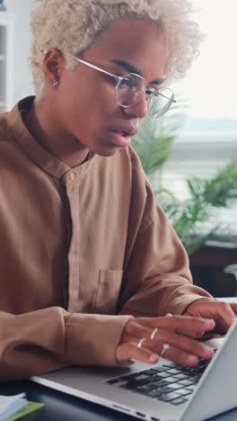 young african american woman journalist typing article in laptop sits in office