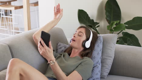 Middle-aged-Caucasian-woman-enjoys-music-on-her-couch-at-home