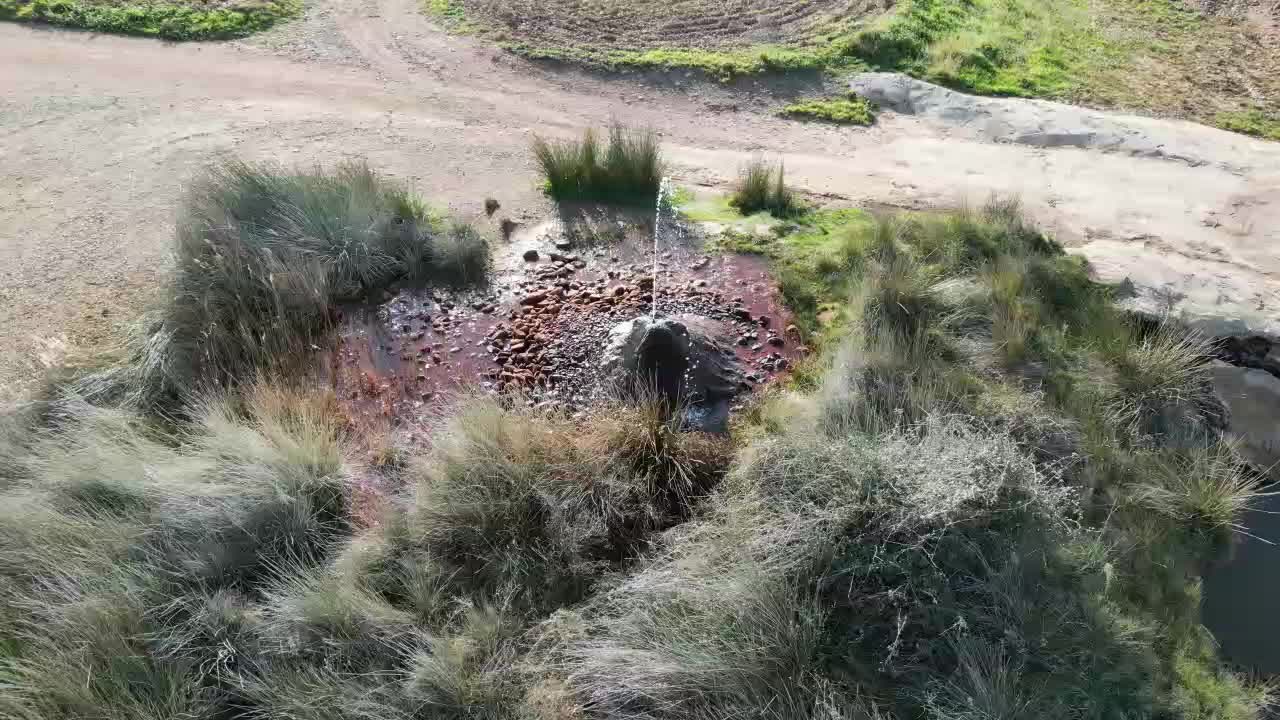 water geyser at Fuendejalon Spain with spurting water and iron deposits.