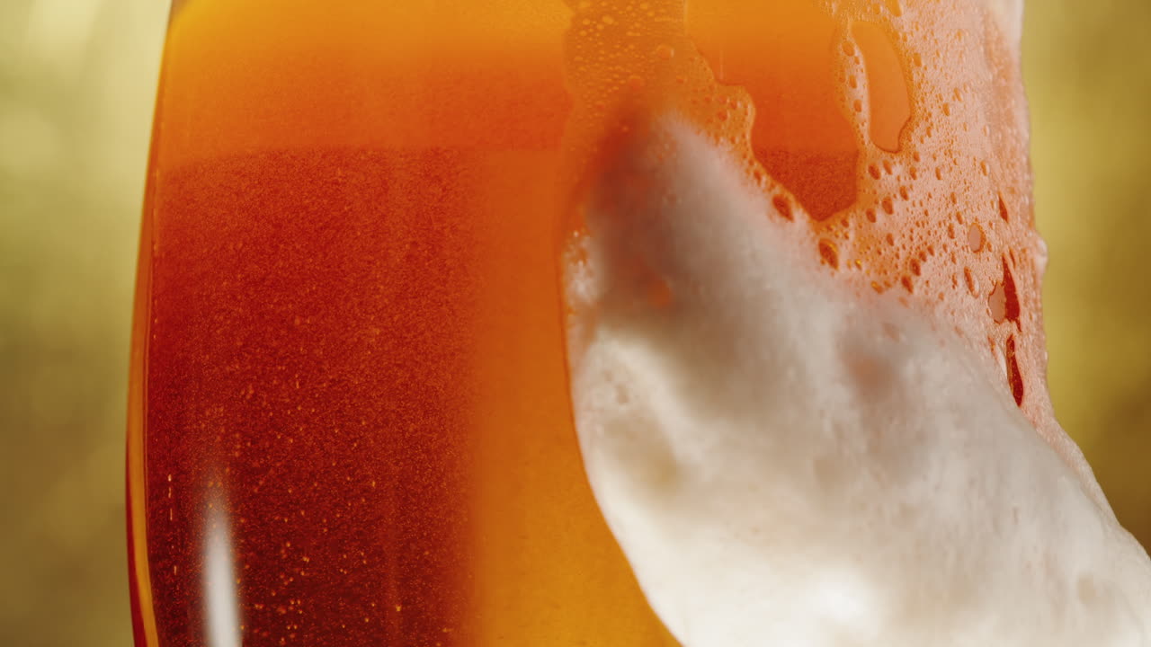 Birra versata in un bicchiere con schiuma densa