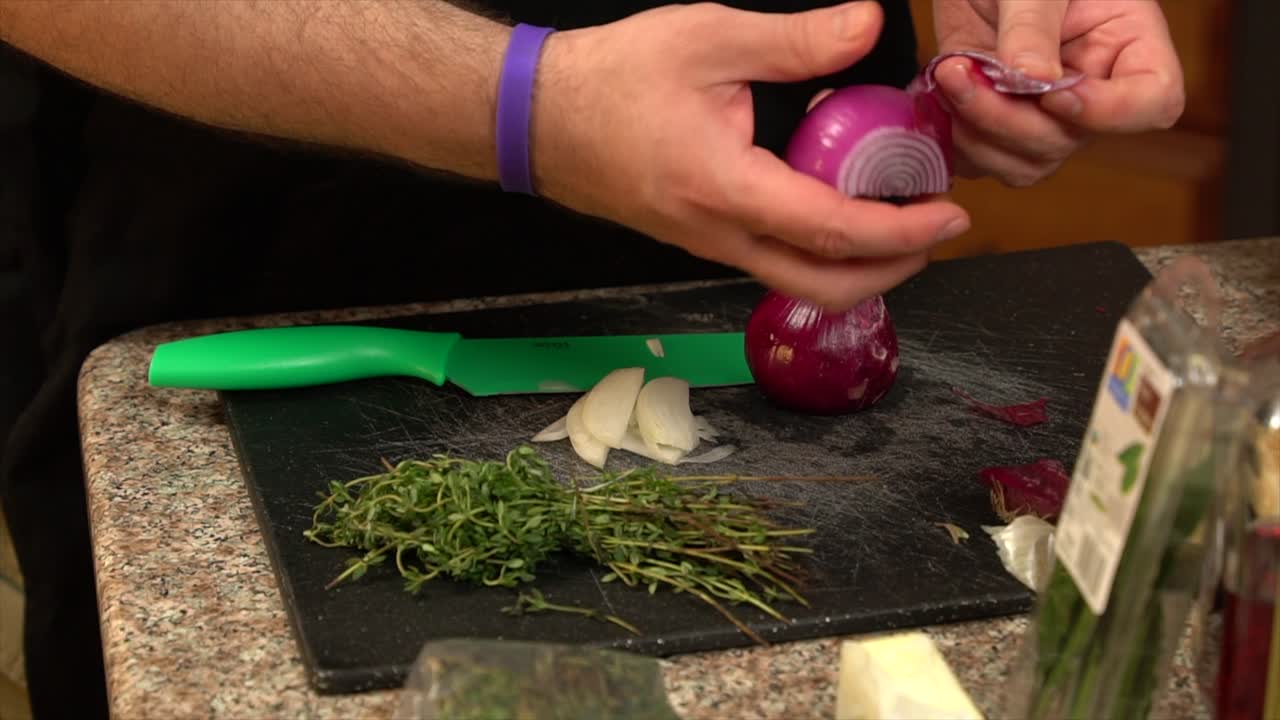Peeling a red onion over a cutting board and knife