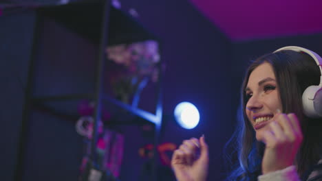 close up profile of woman wearing white headphones looking excited and happy, face illuminated by purple neon lights, subtle smile showing joyful reaction, focused on music in studio environment