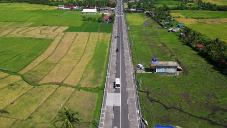 cars driving in the road along the rice fields in malilipot, albay, bicol. - aerial shot