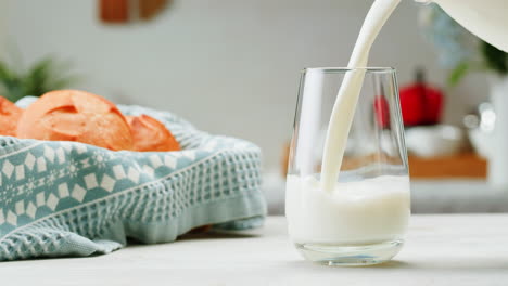 milk being poured into a glass next to bread