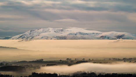 La-Niebla-Cubre-El-Valle-Del-Edén-De-Cumbria-En-Una-Hermosa-Escena-Nocturna-De-Invierno,-Con-Las-Montañas-Cubiertas-De-Nieve-Del-Distrito-De-Los-Lagos-Del-Norte-De-Blencathra-Y-Skiddaw-En-El-Fondo