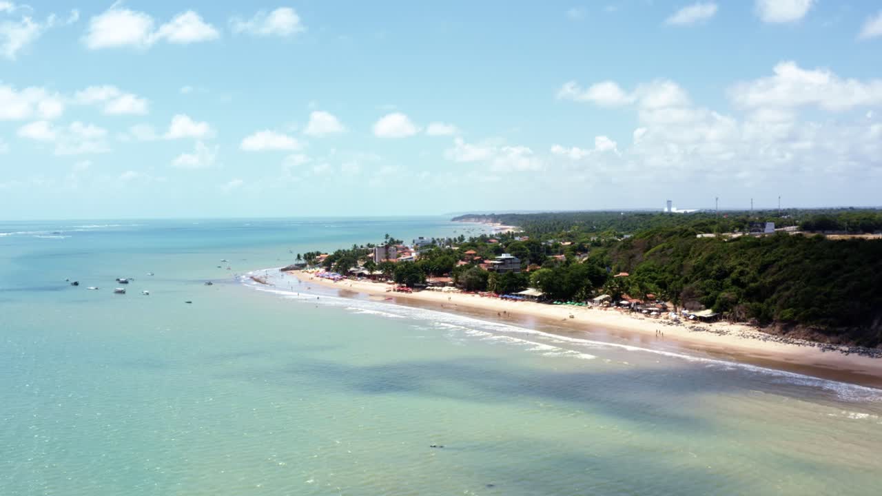 Dolly in aerial drone shot of the beautiful tropical tourist destination of Seixas Beach near Cabo Branco in the beach capital city of Joao Pessoa, Paraiba, Brazil on a sunny summer day