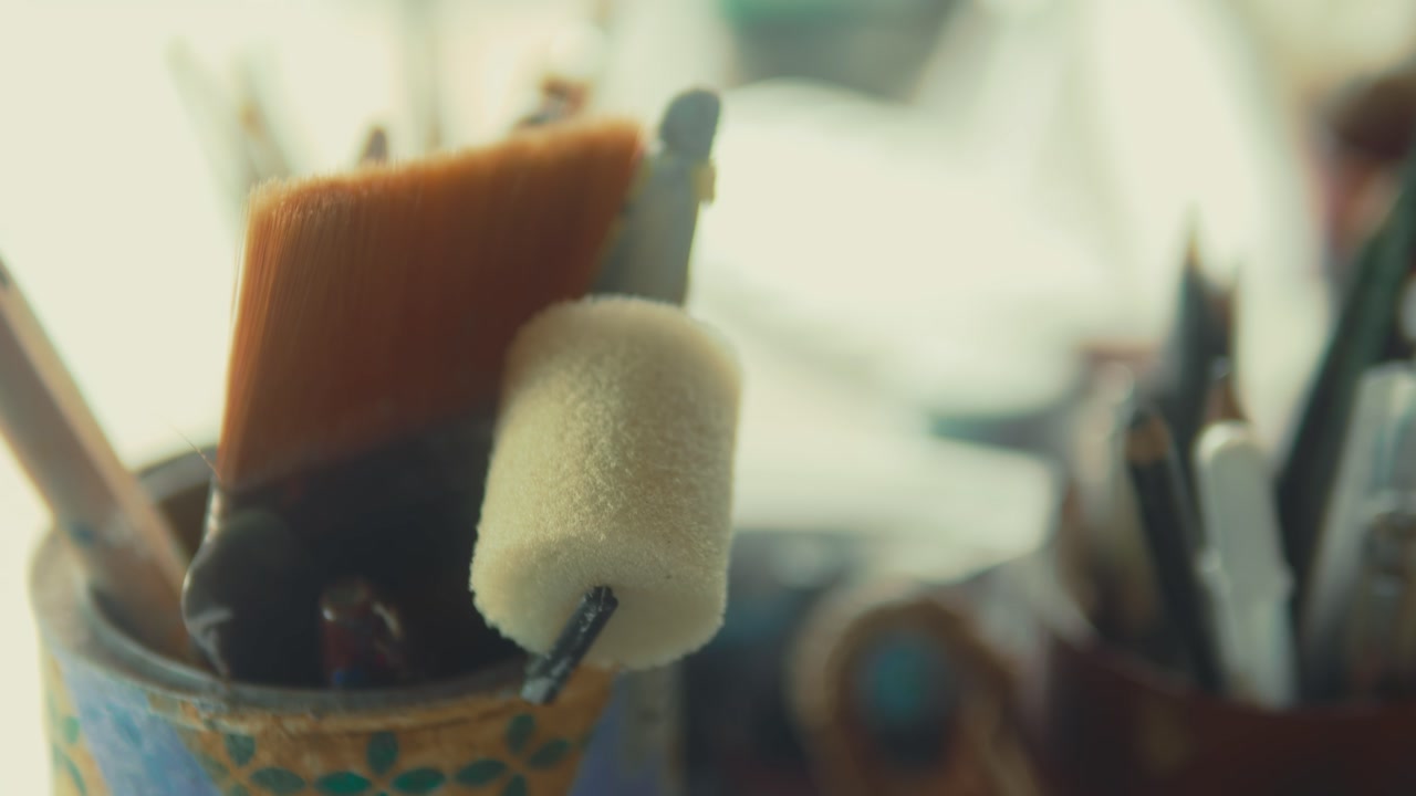 Art tools in cups, creative workspace vibe, focused on brushes, sunny day