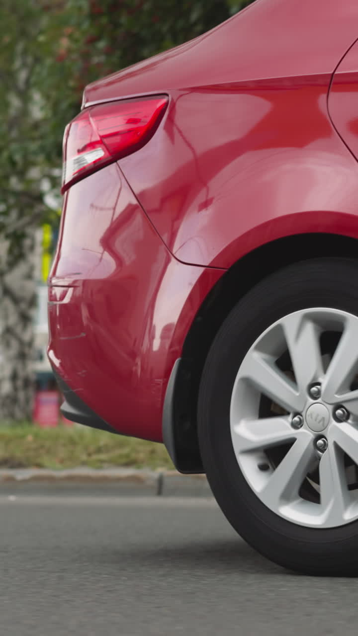 el sedán rojo conduce en una calle vacía pasando por viejos edificios en un soleado día de verano. el elegante automóvil de clase se mueve en la carretera de asfalto en la ciudad de primer plano