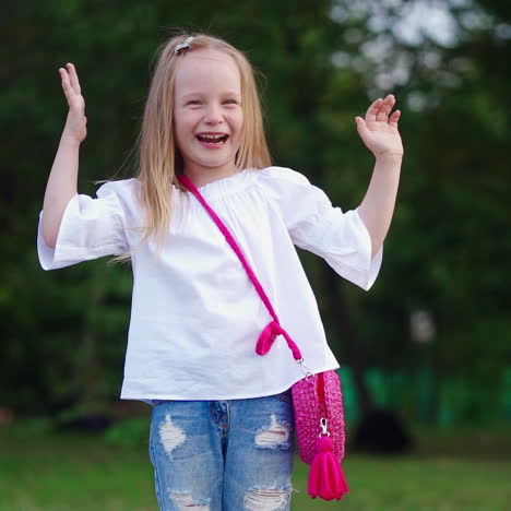 portrait of a happy kid in the green park. pretty little girl smiling and looking at camera on green natural background outdoors. slow motion.