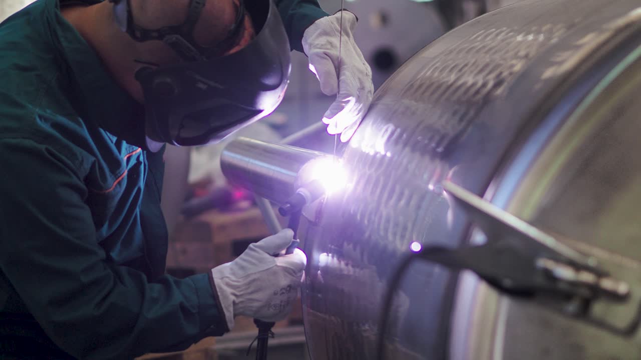 Welder, using VIG, TIG, MIG MAG method to welding stainless steel parts, close up. The welder uses a mask to protect your eyes. Argon welding of stainless steel sheet, parts. Scene N.
