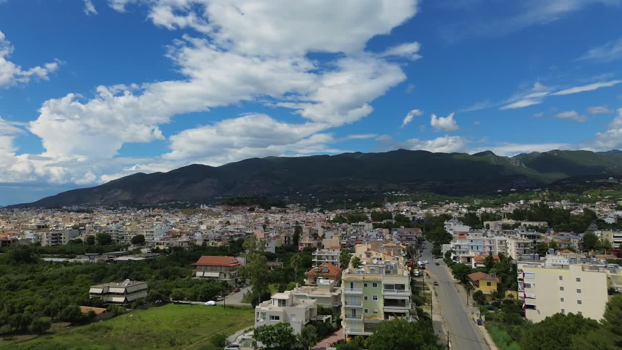 Aerial cityscape view of Kalamata, beautiful blue sky with white cloud formations, footage from Iroon street, at eastern suburbs of city, establishing revealing shot raise up from low altitude 4k