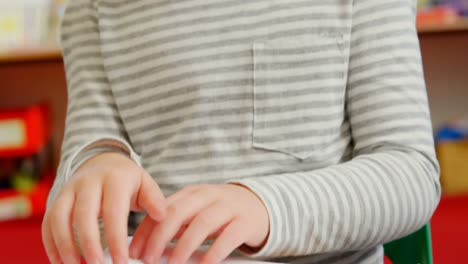 Front-view-of-blind-Caucasian-schoolgirl-reading-a-braille-book-at-desk-in-classroom-at-school-4k