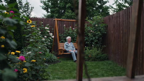 elderly woman relaxing on a swing in a garden