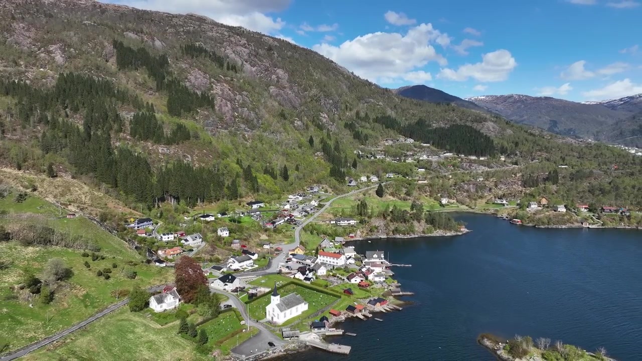 Bruvik Dorf auf Osterøy am Sørfjorden, Norwegen, an einem sonnigen Frühlingstag mit Fjordlandschaft.